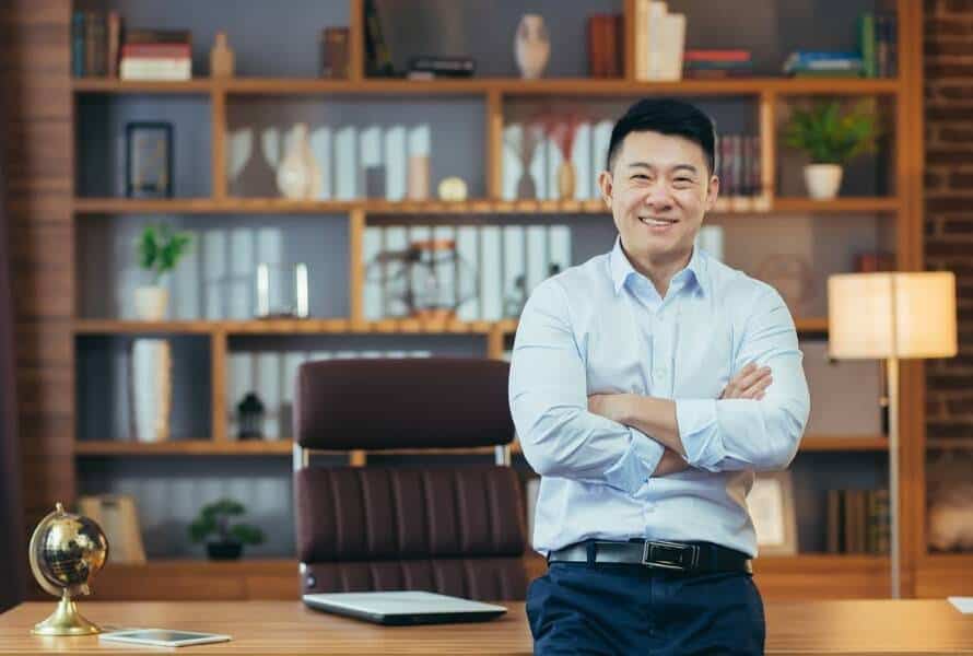 A chief of staff stands smiling at a desk