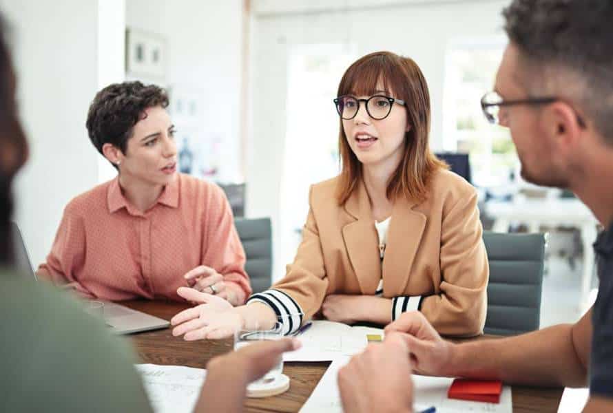 a woman talking to a team of employees in the office